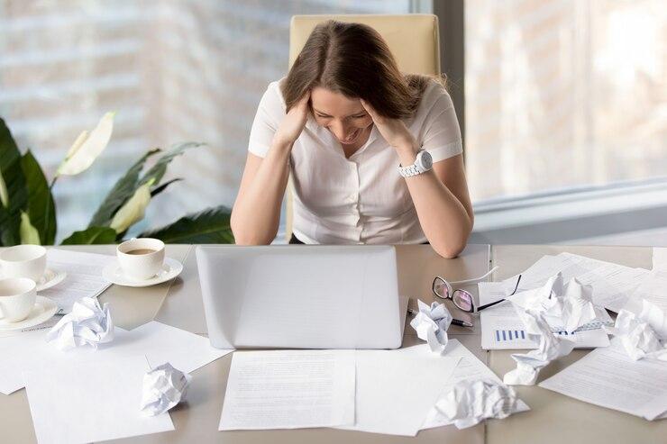 Femme devant son ordinateur au travail devant son e cran avec plusieurs papiers froisse s autour d elle qui fait une crise de nerf