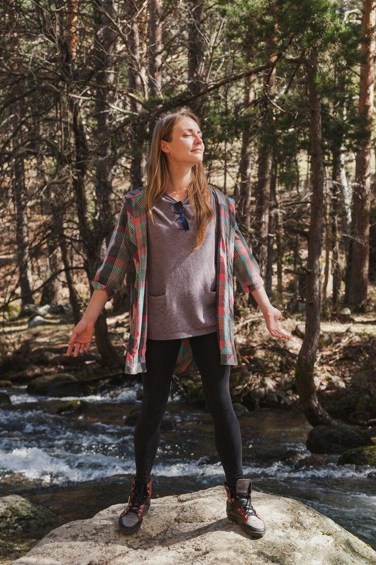 Femme sur un rocher en fore t les yeux ferme s qui ressent la nature