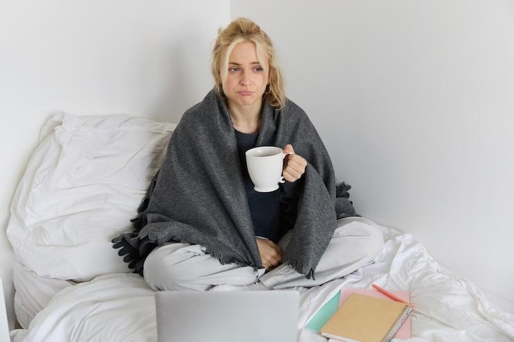 Portrait femme atteinte grippe eternuant se sentant malade assise lit ordinateur portable travaillant